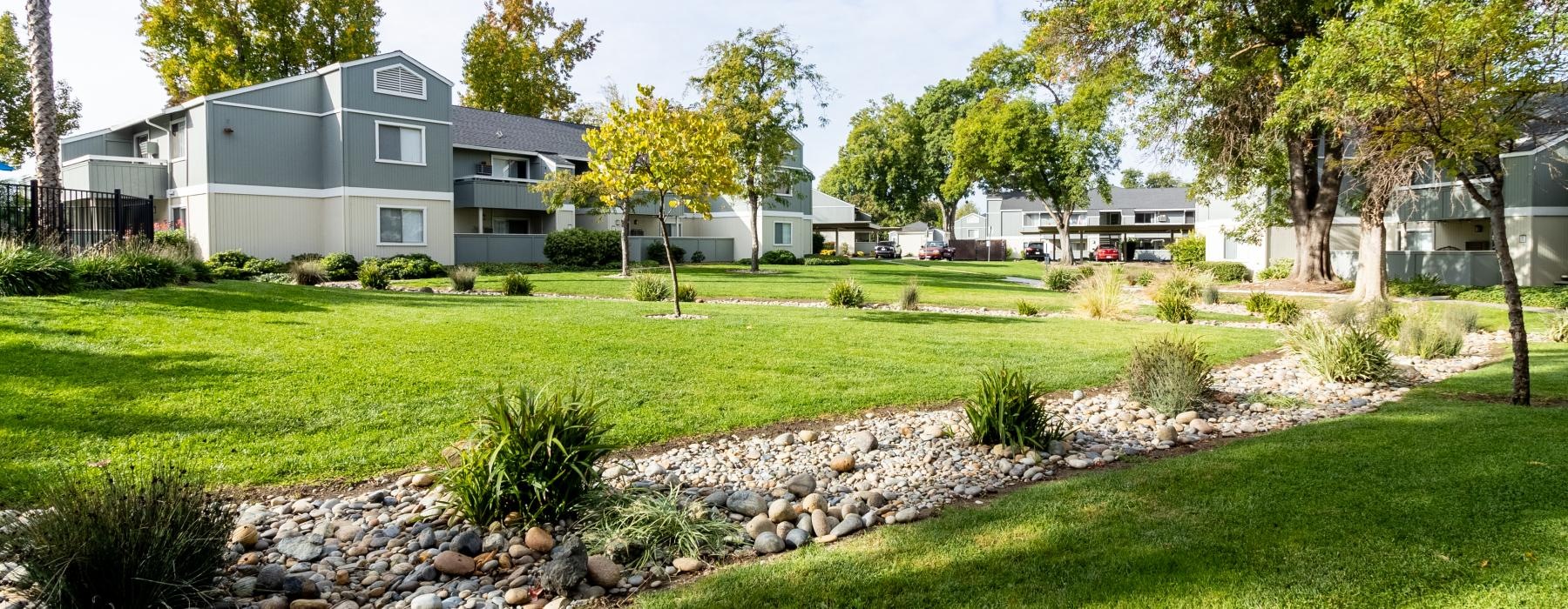 a spacious lawn with a dry creek bed, river rock, and landscaping